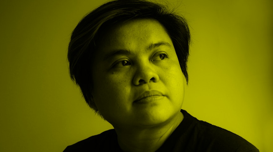 A person with short black hair, light brown skin wearing a t-shirt. They are gazing upwards with a thoughtful expression.