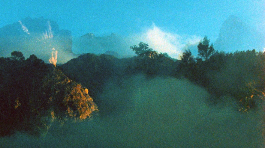Mountain ranges superimposed on a bright blue sky and a misty mountain range.
