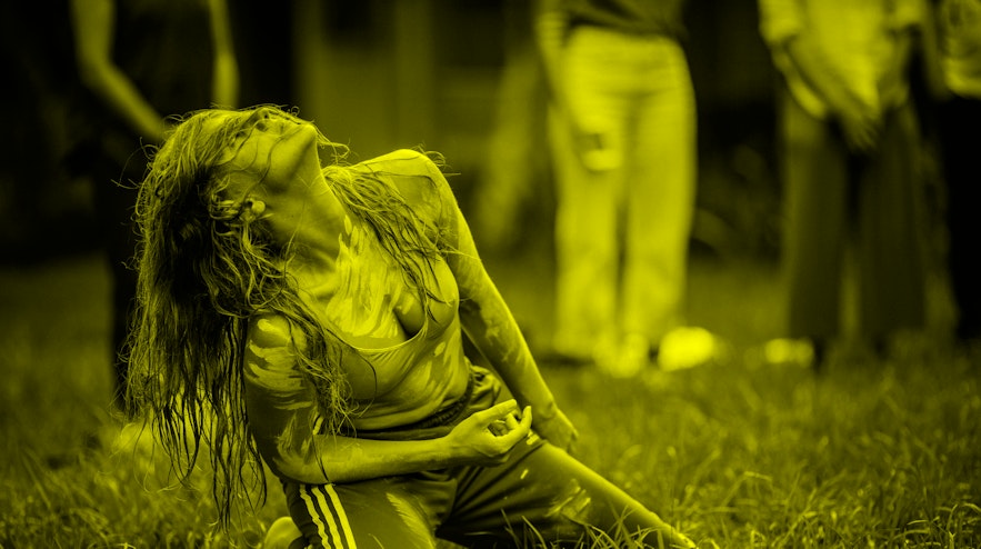 A person on their knees outdoors, throwing their head back and facing towards the sky.