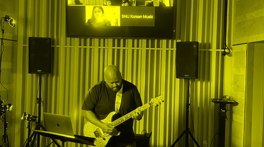 Person playing guitar, standing between two speaker stands