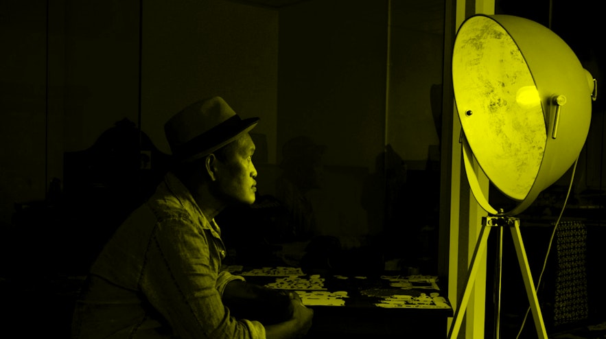 Person sitting in a dark room, looking to the source of light, and old fashioned spotlight