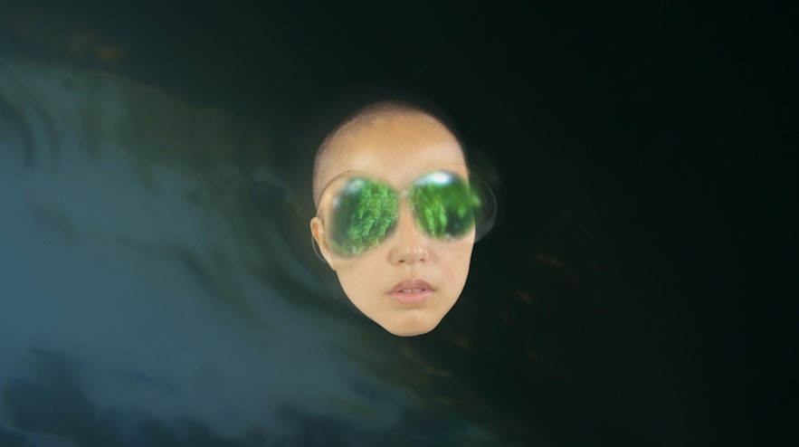 A shaved head without a body with large green shapes over the eyes.