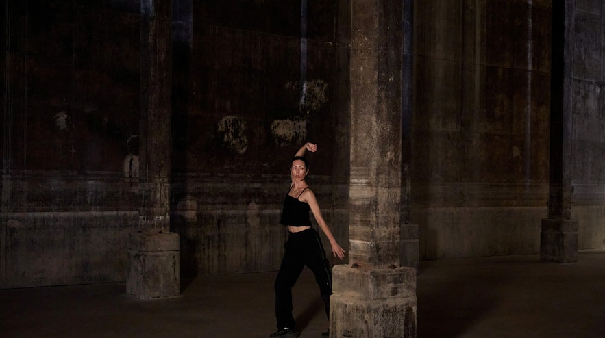 A person stretching one arm above their head in a former World War 2 oil tank space